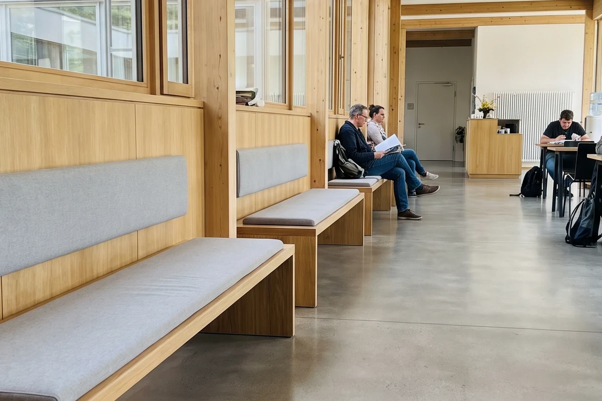 Dünne Polsterauflagen auf langen Sitzbänken in einem öffentlichen Gebäude